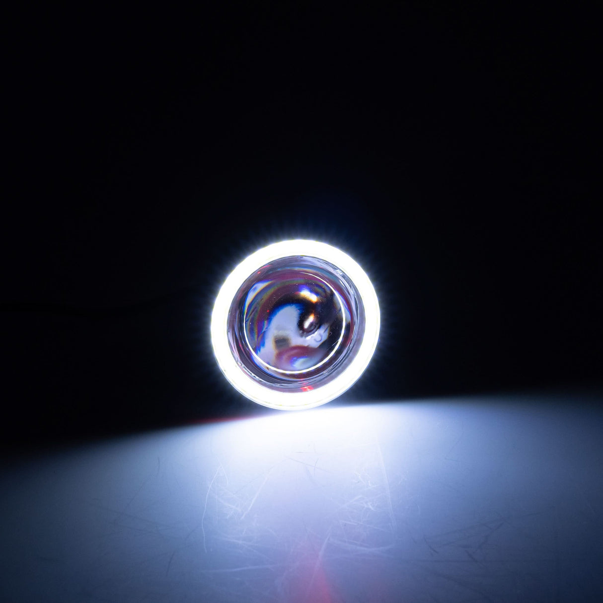 Close-up of a circular headlight for the Coleman AT200-B ATV, featuring a chromed outer ring and a 3-wire harness.