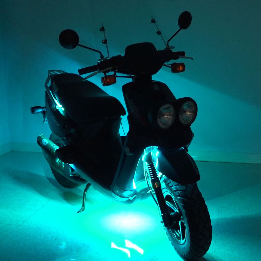 Multi-Color LED Light Kit for Street Scooters, shown installed on a scooter with lights on, illuminating the wheels and headlight for enhanced visibility and aesthetic appeal.