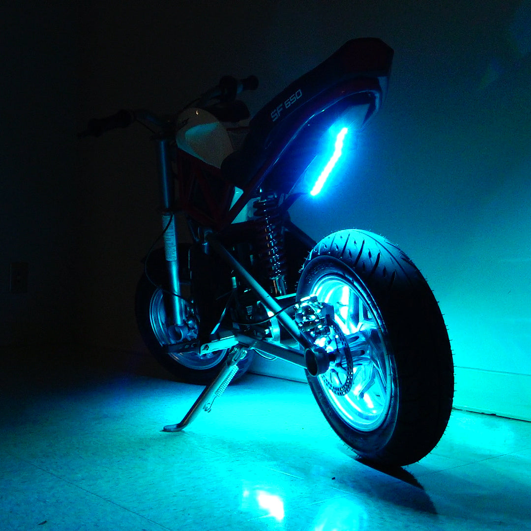 Multi-Color LED Light Kit for Razor Electric Bikes & Scooters shown installed on a motorcycle, highlighting vibrant blue lights, a close-up of a wheel, and a kickstand.
