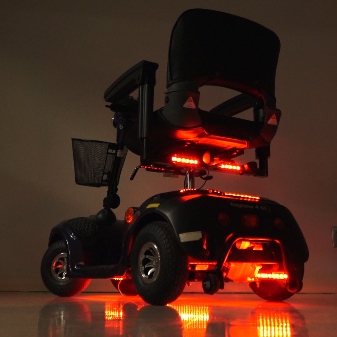 Multi-Color LED Light Kit for Mobility Scooters & Power Chairs: A black electric wheelchair equipped with red LED lights, showcasing a sleek design and advanced lighting features for enhanced safety and aesthetics.