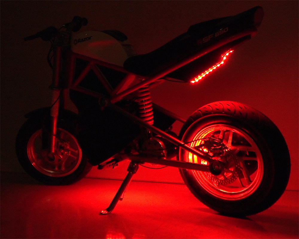 Multi-Color LED Light Kit for Razor Electric Bikes & Scooters, featuring a motorcycle with red LED lights illuminating its wheels and frame, showcasing customizable light functions for enhanced visibility and style.