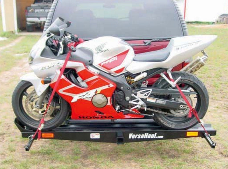 Sport Bike Carrier mounted on a trailer, securely holding a red and white motorcycle with visible tie-down bars and wheel stop.