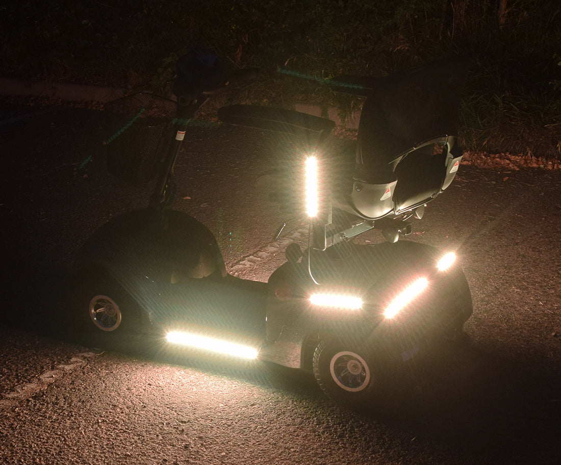Multi-Color LED Light Kit for Pride Mobility Scooters shown on a scooter with lights on, highlighting the vibrant illumination and wheel detail, perfect for enhancing visibility and style.