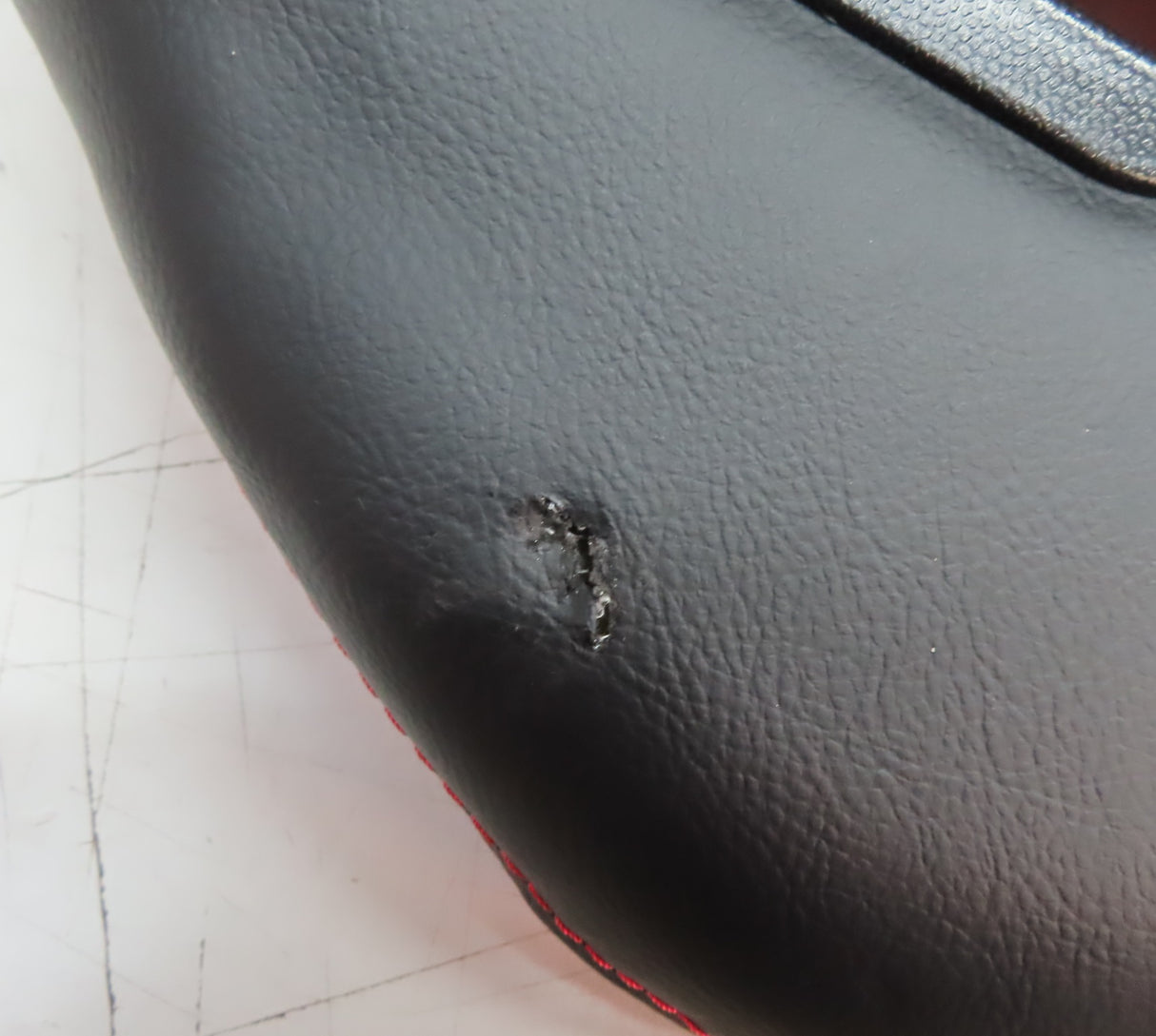 Black leather surface of the 31-1/2 Red Double Seat for the Coleman KT196 Go-Kart (Blemished), featuring a small hole and convenient back vents for securing seatbelts.