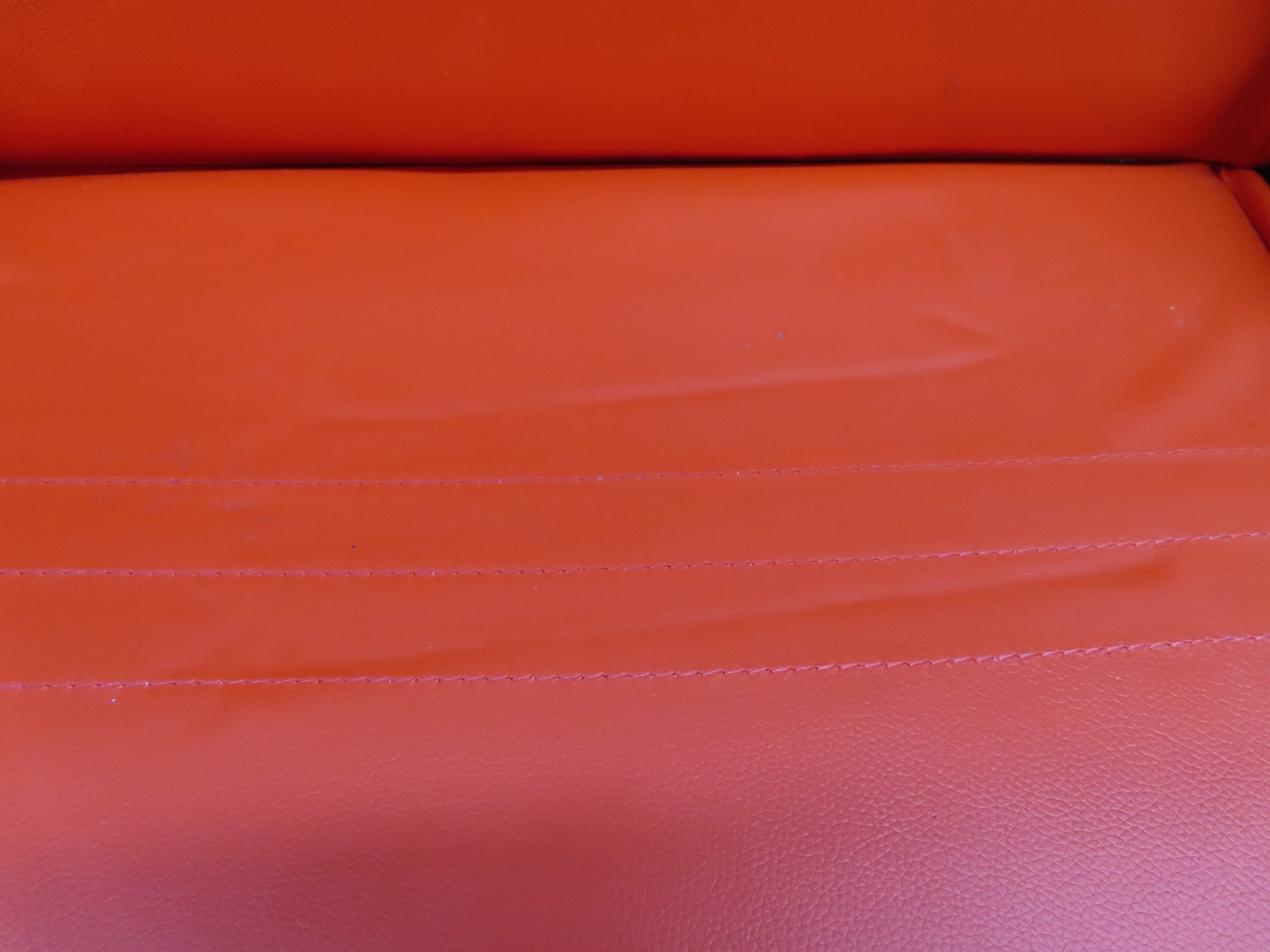 Close-up of the 31-1/2 red double seat for the Coleman KT196 go-kart, highlighting the leather finish and stitching, with visible back vents for securing seatbelts.