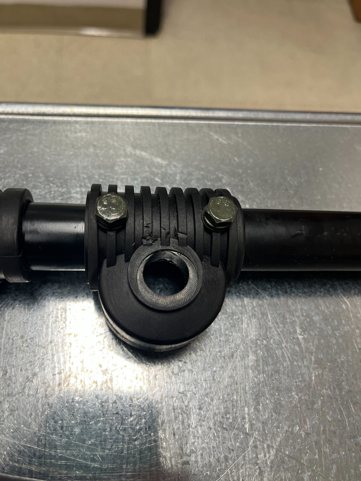 Steering Gear Assembly for the Coleman KT196 196cc 6.5 Hp Go-Kart (Blemished), featuring a black pipe with a central hole, nuts, bolts, and metal surface details.