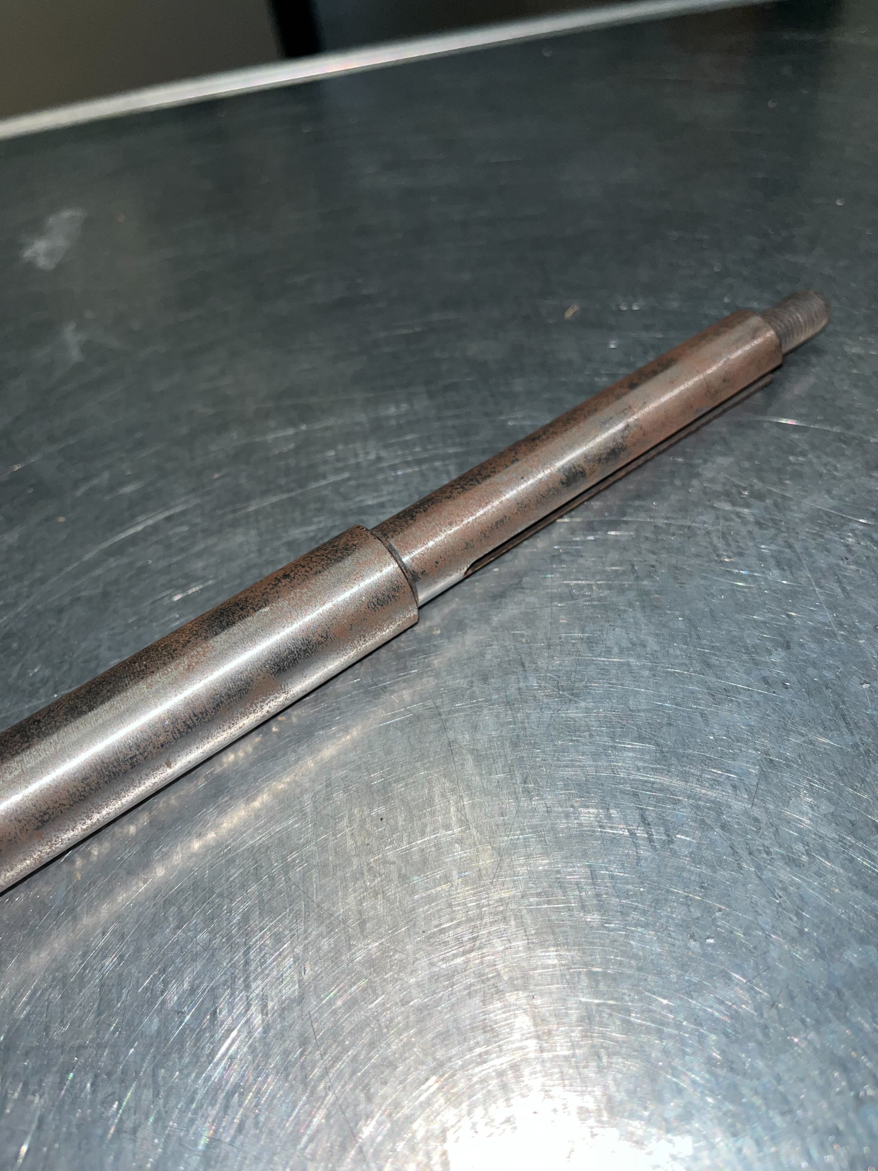 9.20 Sprocket Shaft for the Realtree RTK200 196cc Go-Kart (Blemished) shown on a metal surface, highlighting its stepped rod design and threaded end. Minor surface rust visible.