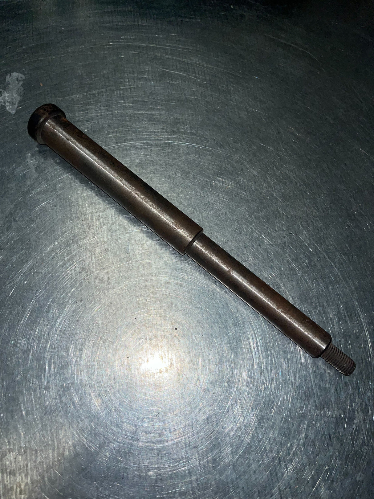 9.20 Sprocket Shaft for the Realtree RTK200 196cc Go-Kart (Blemished) shown on a table, featuring a stepped rod with an M10-1.25 threaded end and slight surface rust.