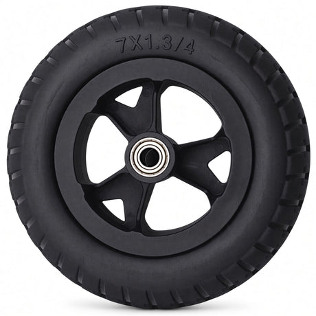 Golden Cricket Travel Power Chair Wheel - A black rubber wheel with a multi-spoke hub and a visible silver ball bearing in the center, photographed on a clean white background. The tire size '7X1.