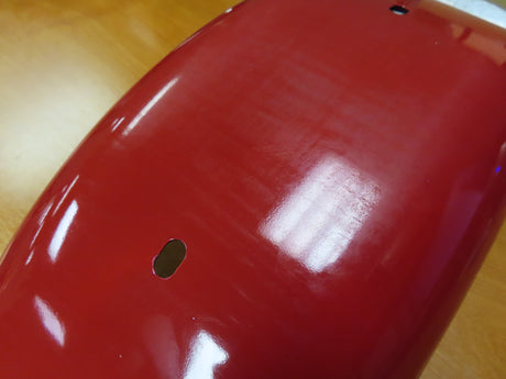 Fender for the Coleman CT200U Trail (Blemished) displayed on a wood surface, highlighting its smooth finish and compatibility with the CT200U Trail mini bike, available in both front and rear configurations.