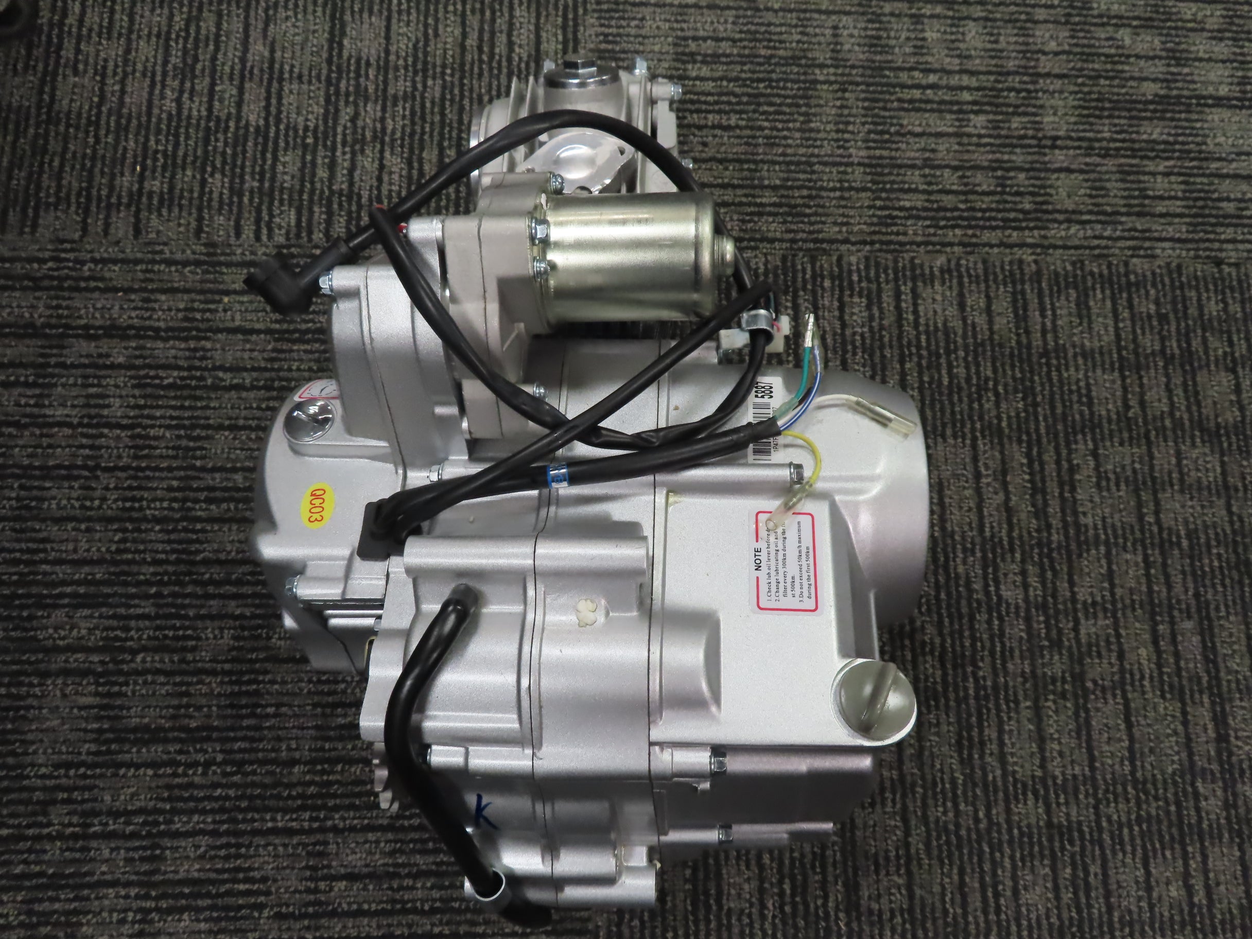 50cc 4-Stroke Auto-Clutch Electric Start Honda-Clone ATV Engine (Blemished) shown on a carpet, featuring black wires, chain cover, carburetor joint, and mounting hardware.