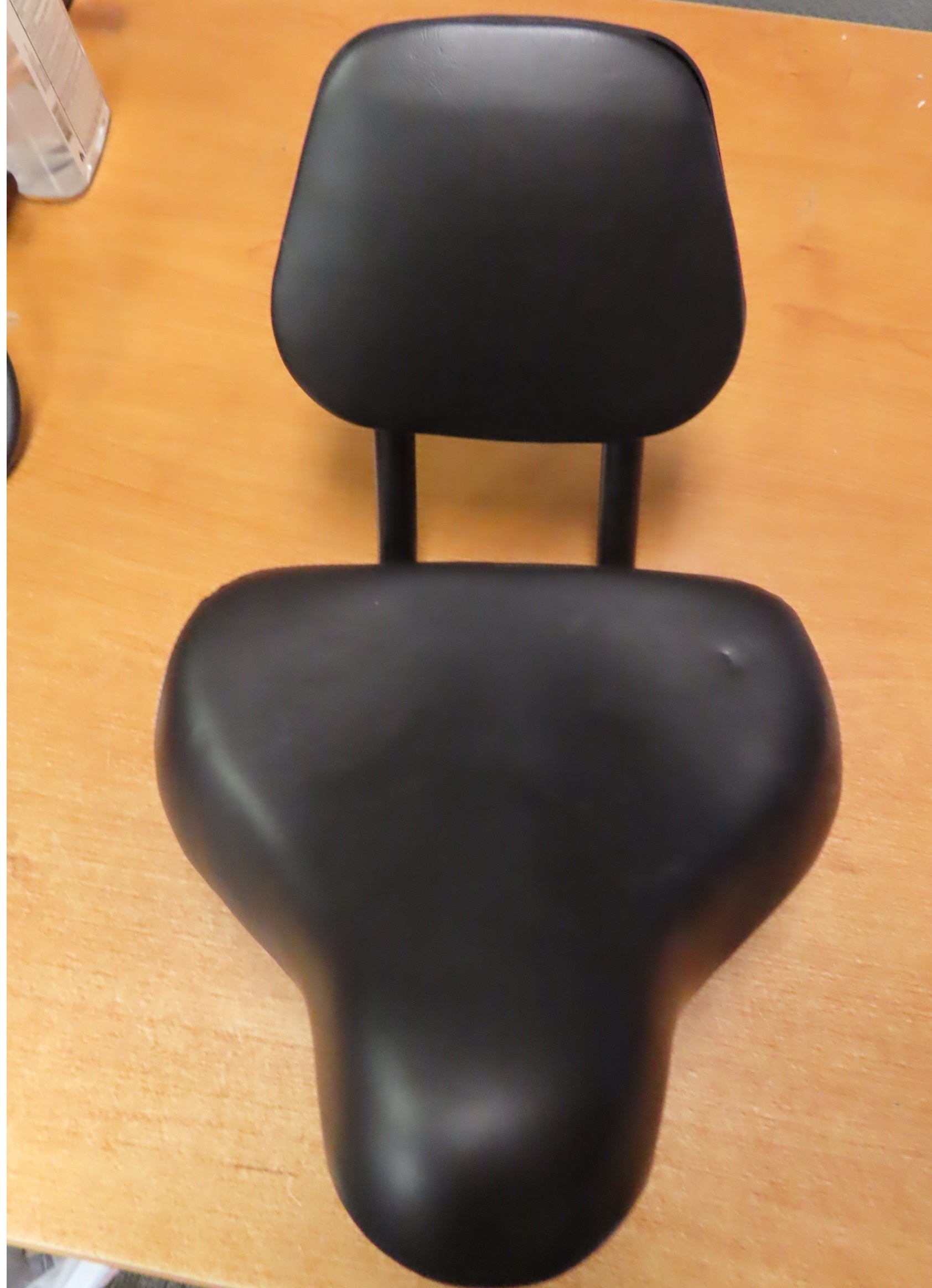 Backrest Saddle Seat for Bikes & Scooters (Blemished) on a wooden surface, showcasing its comfortable black design with an integrated adjustable backrest for maximum riding comfort.