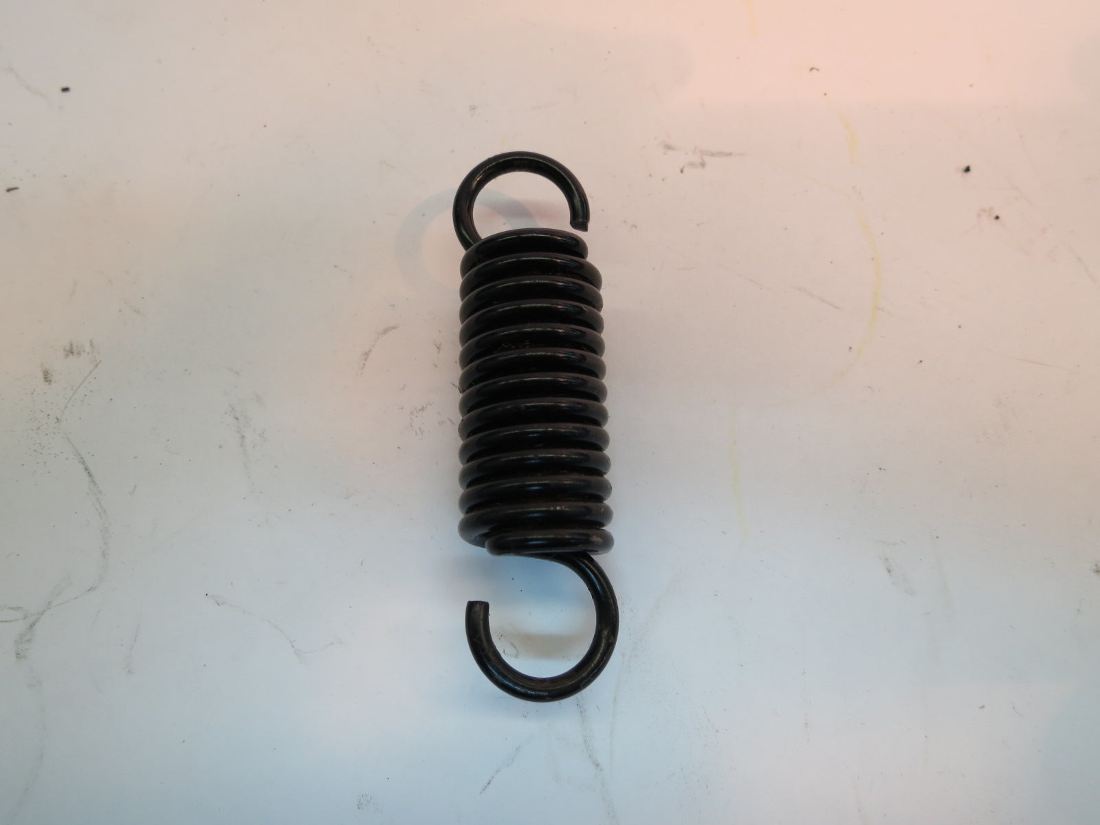 Caster Arm Spring for the Jazzy 614 and 614HD (Used); a close-up of a black coil spring on a white surface, part of the front caster assembly for power chairs.