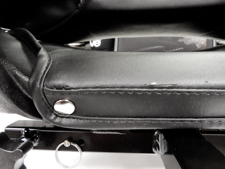 Close-up of a slightly blemished 17 Wide Molded Seat Assembly for Go-Go and Pride Mobility Scooters, highlighting the black leather seat and minor scratches on the plastic hinges.