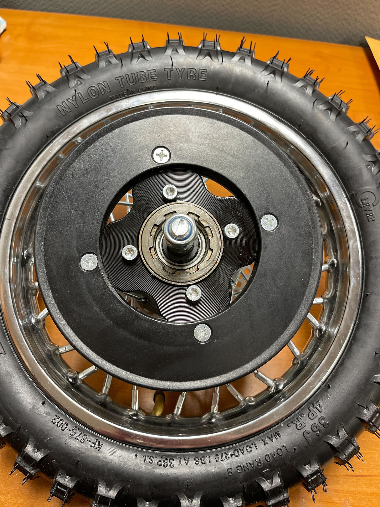 Rear Wheel Assembly for Razor MX500 and MX650 (Blemished): Features a metal rim, black tire, axle, sprocket, brake rotor, freewheel, and visible screws.