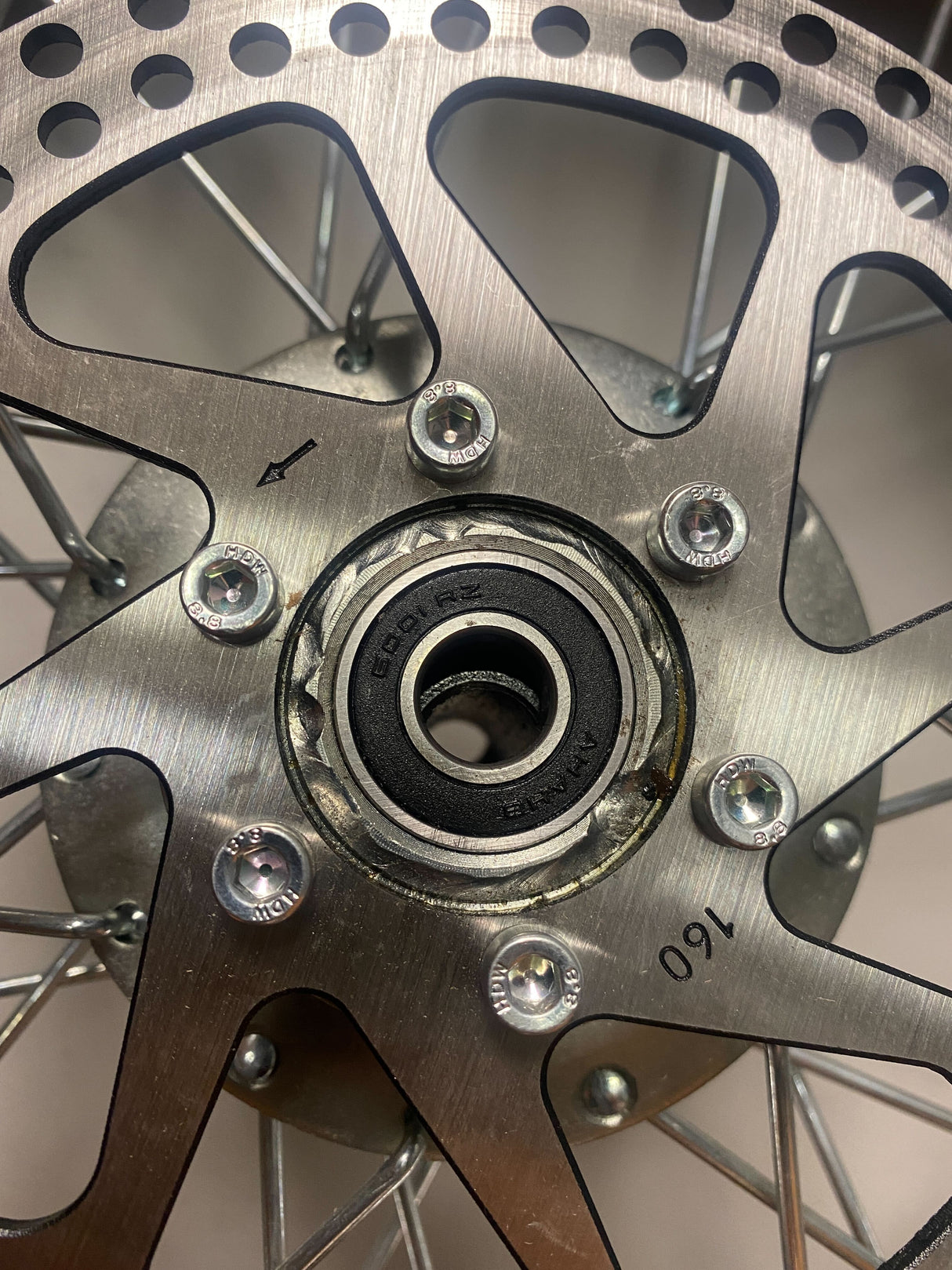 Front Wheel Assembly for Razor MX500 and MX650 (Blemished) featuring a close-up of the wheel, disc brake rotor, and spokes, highlighting the visible screws and metal parts.