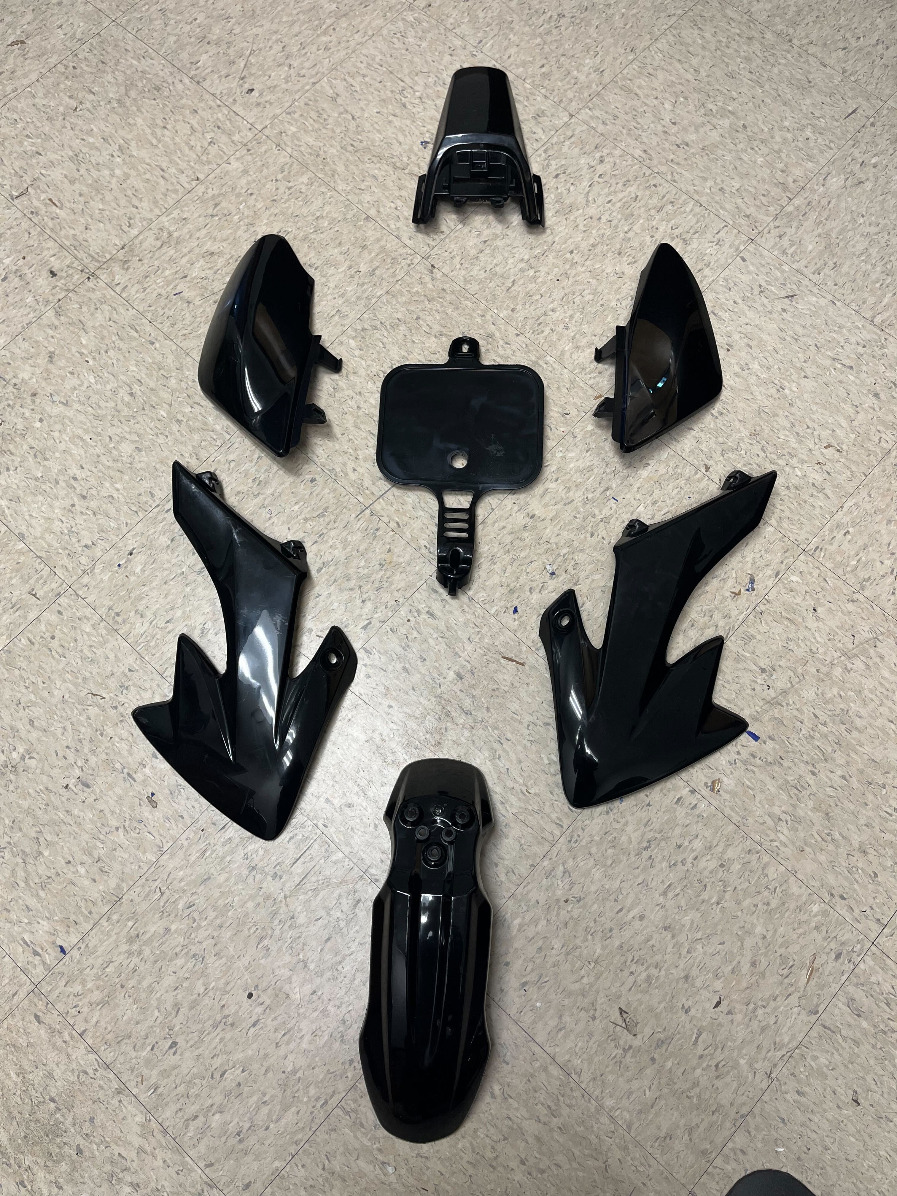 Honda CRF Style 50cc - 70cc Dirt Bike Fender & Body Panel Set (Small) (Black) (Blemished) shown disassembled on a tile floor, including fenders, side covers, panels, and a number plate.