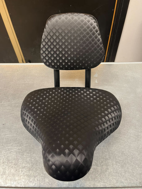 Bicycle Saddle Seat with Backrest (Missing Hardware) displayed on a table, featuring a comfortable black saddle, metal handles, and a supportive backrest designed for various bicycle styles.