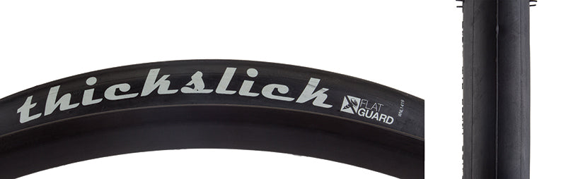 Close-up of a 700x25 ThickSlick Flat Guard Bicycle Tire, showcasing the slick tread and visible white text. The image highlights the tire's robust design, ideal for durability and puncture resistance.