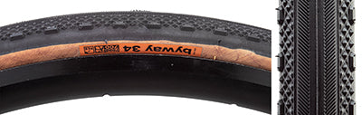 Close-up of a 700x34 Black/Tan Byway TCS Bicycle Tire, showing the smooth rolling centerline transitioning to diamond-shaped peaks and substantial shoulder knobs designed for traction.