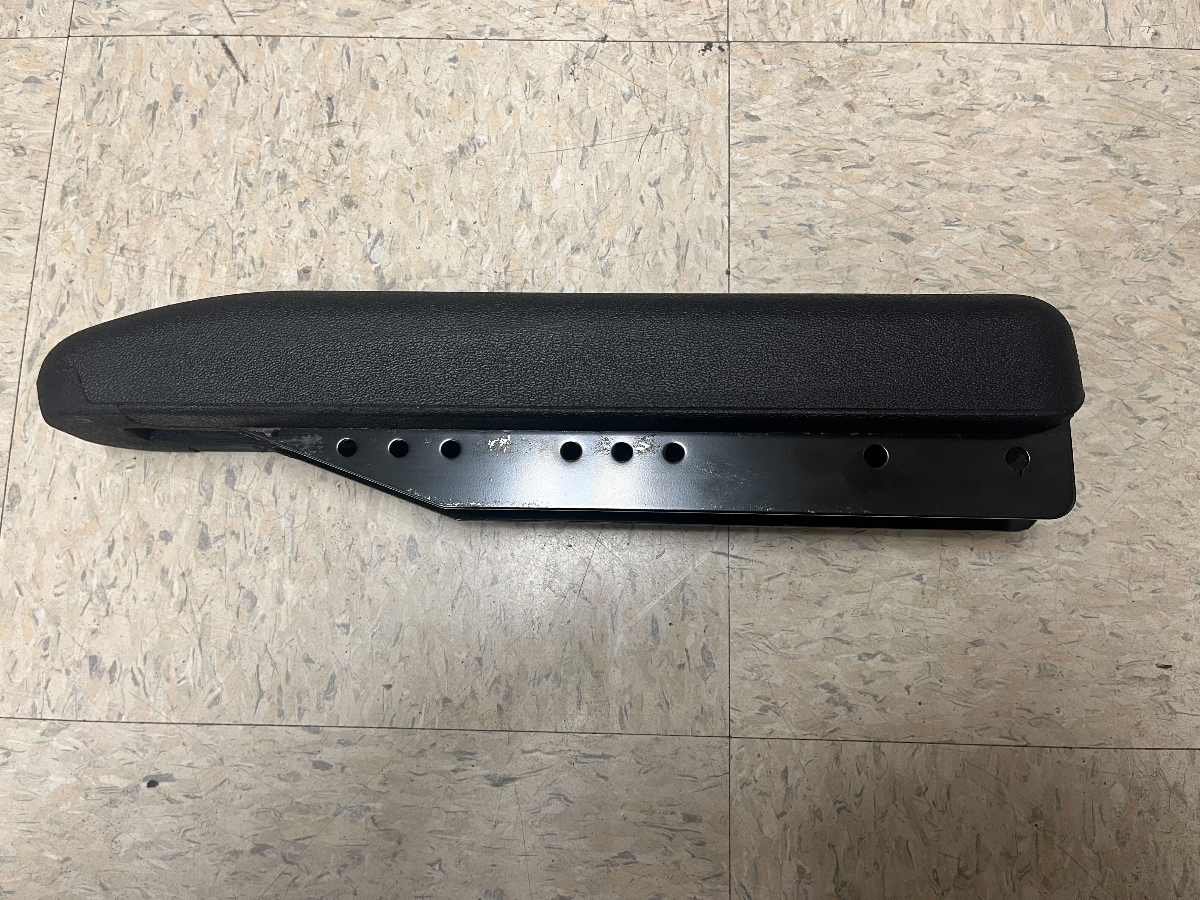 Full Length Urethane Armrest Pad for Invacare Power Chairs (Blemished) on a tile floor, showcasing black and silver surface with holes, designed for easy installation and arm support.