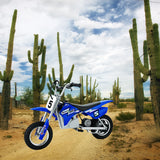 Blue Razor MX350 Dirt Rocket motorcycle in a desert setting. Visible close-up of a wheel and a white sign with a number. Suitable for 24 Volt Battery Pack, Versions 9+.