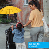 Woman holding a child's hand beside a stroller with a Universal Grip Umbrella Holder for Mobility Scooters, Power Chairs, & Wheelchairs, showcasing its adjustable and flexible arm feature for optimal positioning.