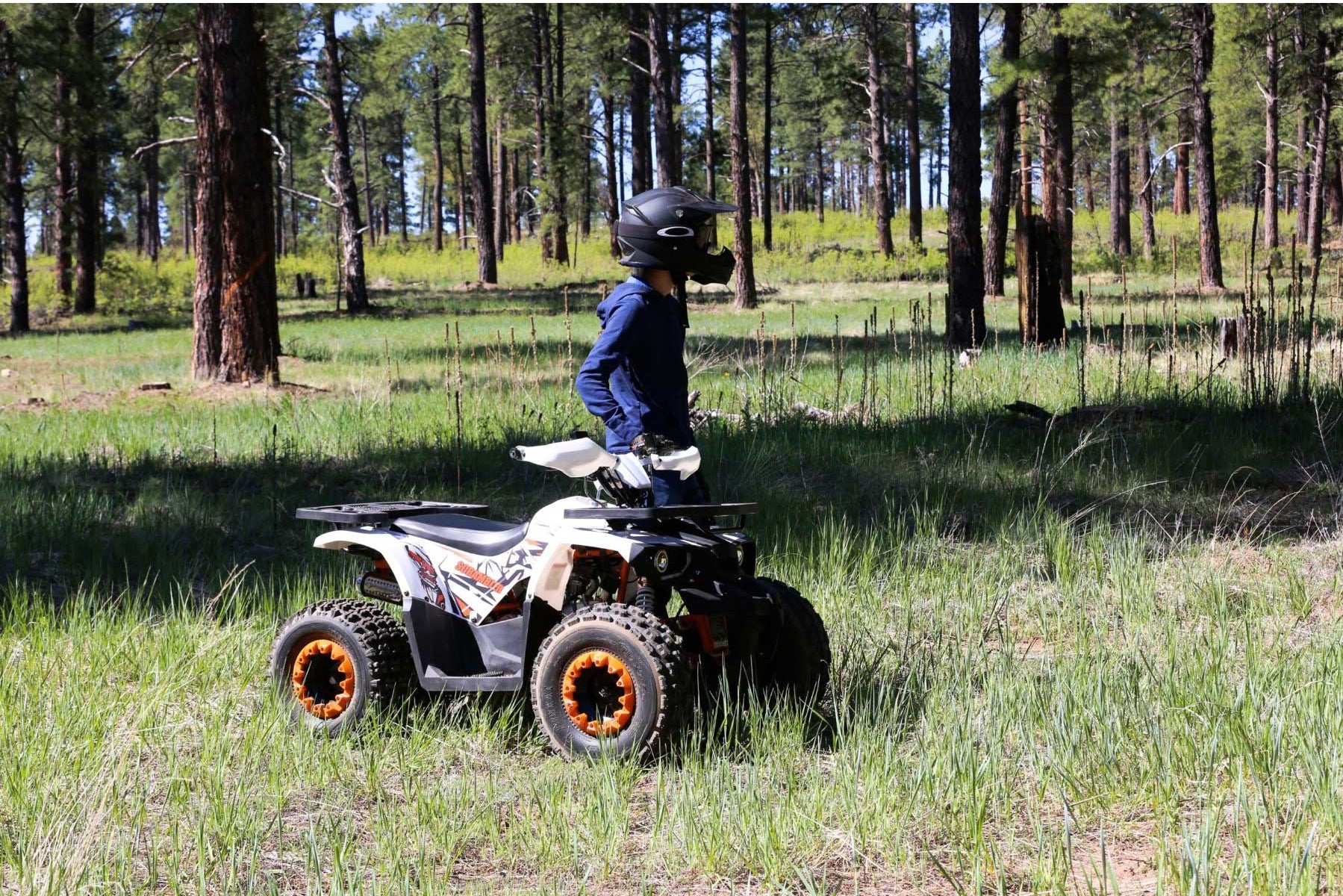 A person riding a quad bike in a forest, showcasing the vehicle's components like the A7RTC spark plug, a reliable replacement part for various scooter and motorbike engines.