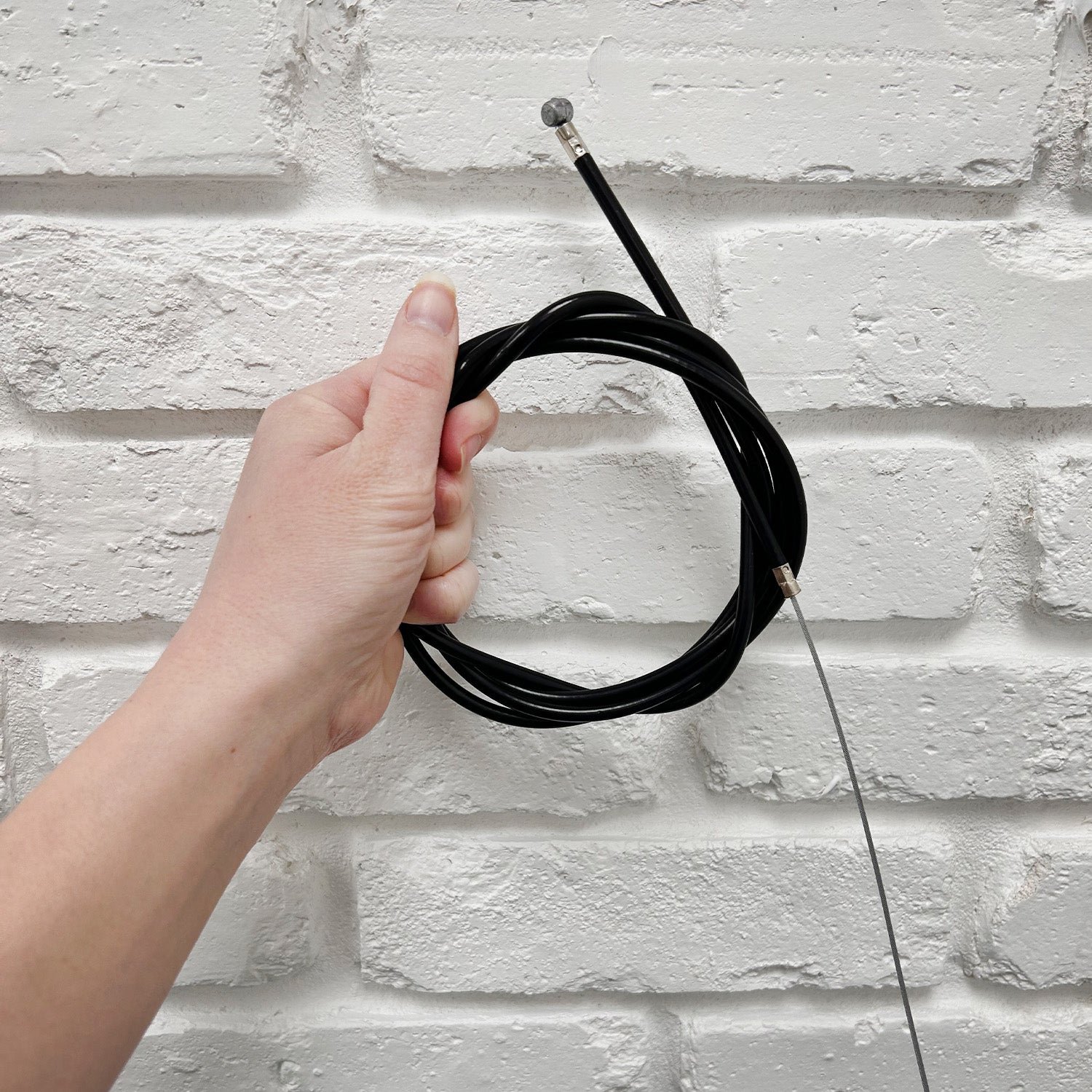 A hand holding a 59 Scooter Brake Cable designed for gas and electric scooters.