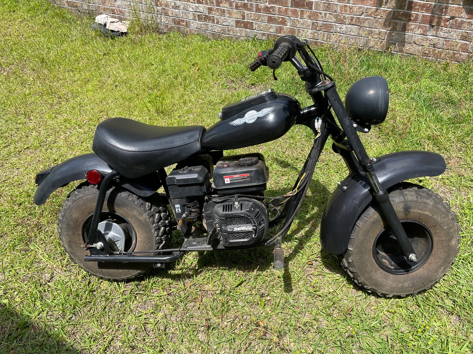 Throttle Return Spring for the Baja Mini Bike MB200 - VIN Prefix LYOY, depicted on a black motorcycle parked on grass, essential for the bike's control system.