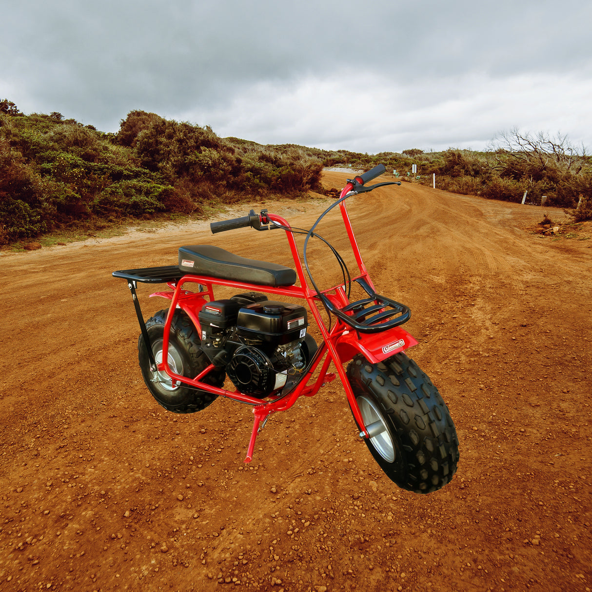 Seat for the Coleman CT200U Mini Bike (Blemished) displayed on a red mini bike parked on a dirt road, showcasing its black, contoured design suitable as a replacement part.