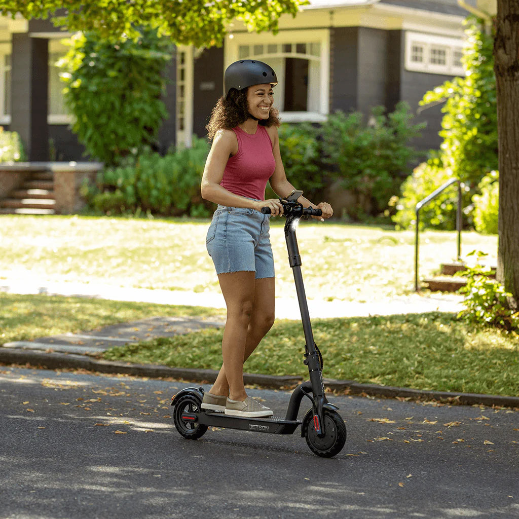 Woman riding a scooter, illustrating usage of the 24 Volt Universal Battery Wiring Harness Kit for electric scooters, highlighting its role in connecting new batteries to existing wiring efficiently.