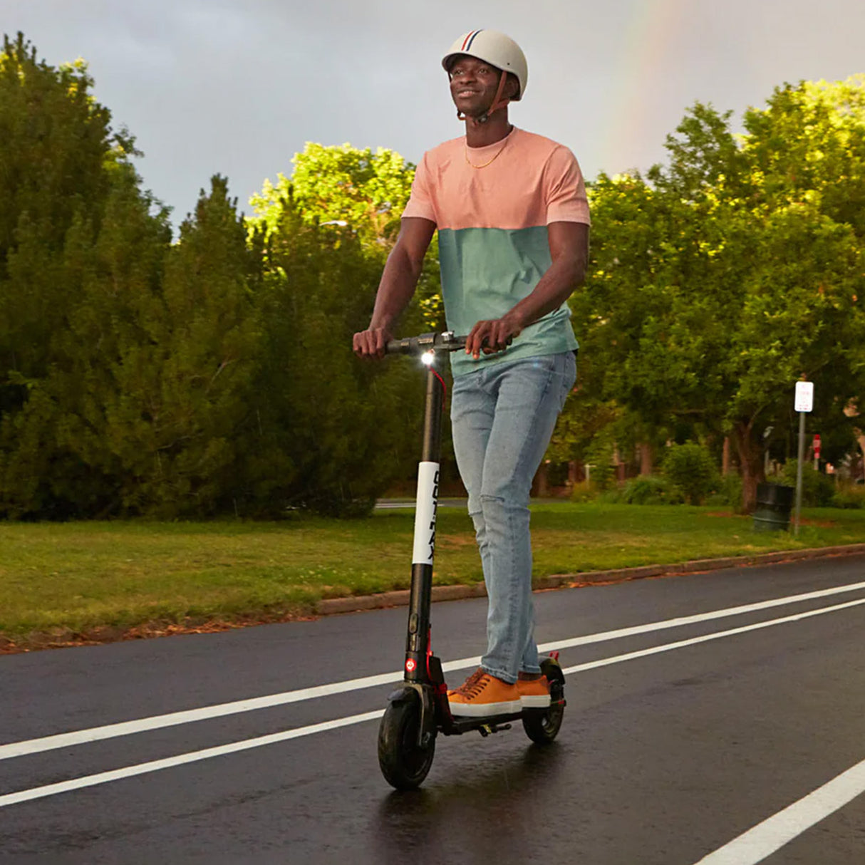 Man riding a scooter on a road, highlighting the need for a Coaxial Charger Port for GOTRAX GXL, GXL V2, G4, Flex, & XR Ultra Electric Scooters, essential for maintaining battery charge.