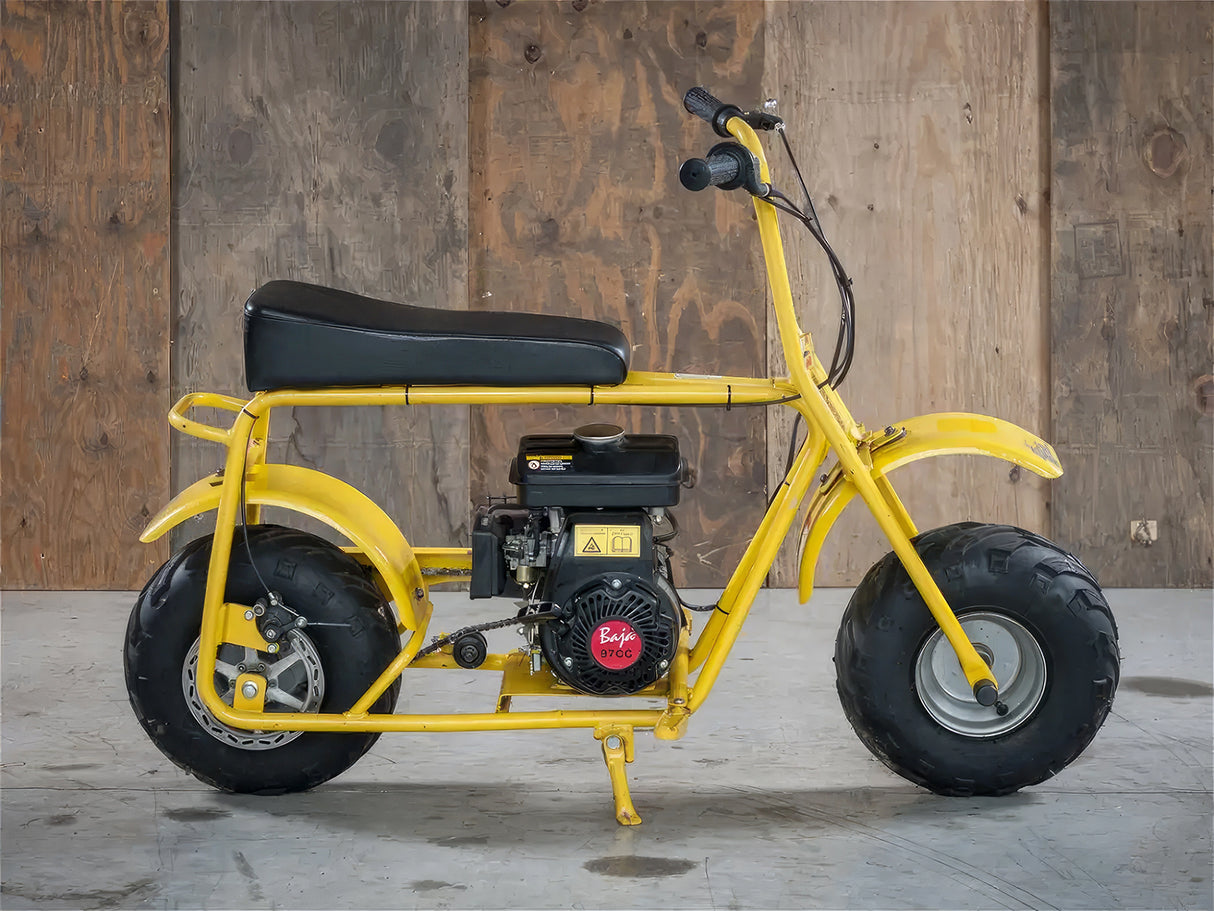 Straight Governor Throttle Return Spring for the Baja Doodle Bug Mini Bike (DB30R) shown installed on a yellow mini bike with a black seat, highlighting its placement near the engine and wheel.