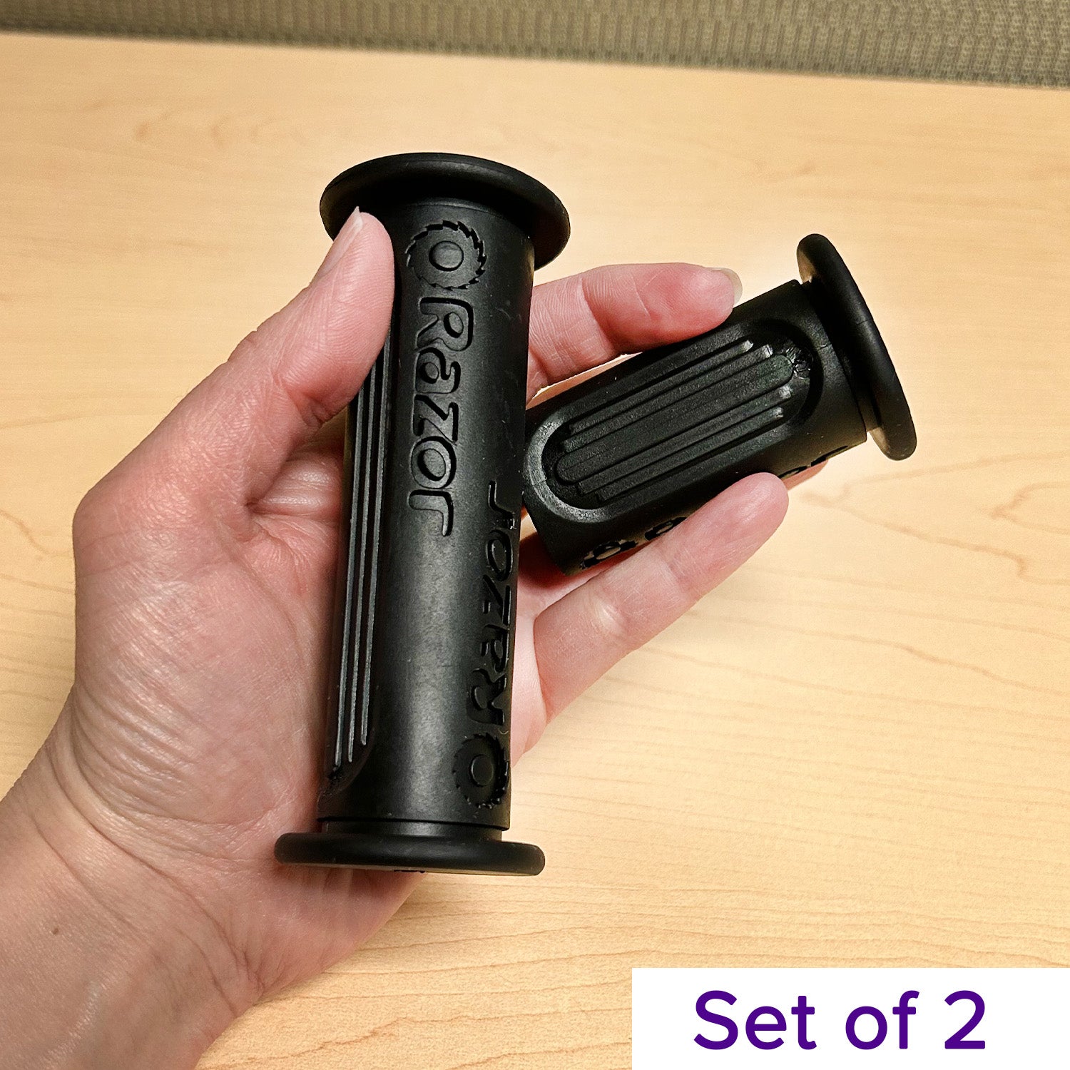 Hand holding the Handlebar Grip Set for the Razor Dirt Quad 500 (Version 1+), showing both a full-length and a half-length black grip, designed for secure and comfortable riding.