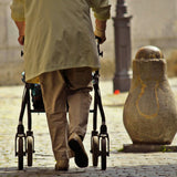 Person using the Drive Medical Durable 4-Wheel Rollator (10257) with visible hand brake and cable, featuring convenient loop handles.