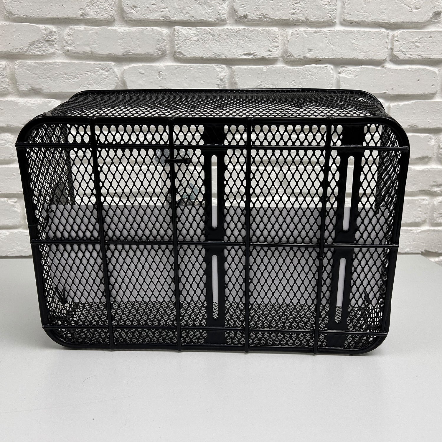 Market-Style Rear Basket for Bicycles (Axiom) - Black metal wire mesh basket with an open top, mounted on a white surface, designed for rear bike racks, features sturdy construction and a cut-away section for seat clearance.