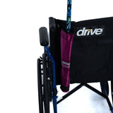 Universal Cane Holder for Mobility Scooters & Power Chairs, attached to a wheelchair backrest with an adjustable nylon strap, holding a cane in a ripstop fabric pouch.