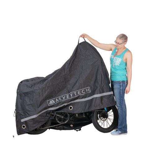 A woman holding the Universal Deluxe Electric Bike & Scooter Weatherproof Cover over a motorcycle, demonstrating its size and ease of use.