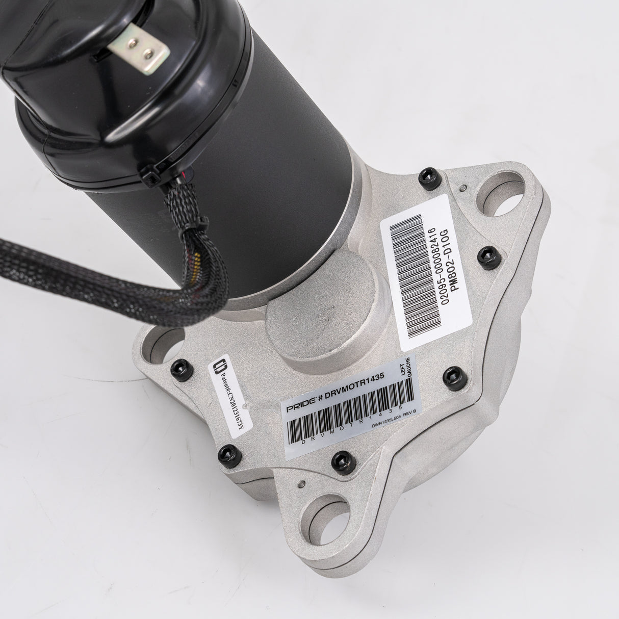 Close-up of the Left Motor and Gearbox Assembly with Freewheel and Mounting Hardware for the Jazzy Select, showcasing intricate mechanical parts including a black cylinder, metal pieces, and a barcode.