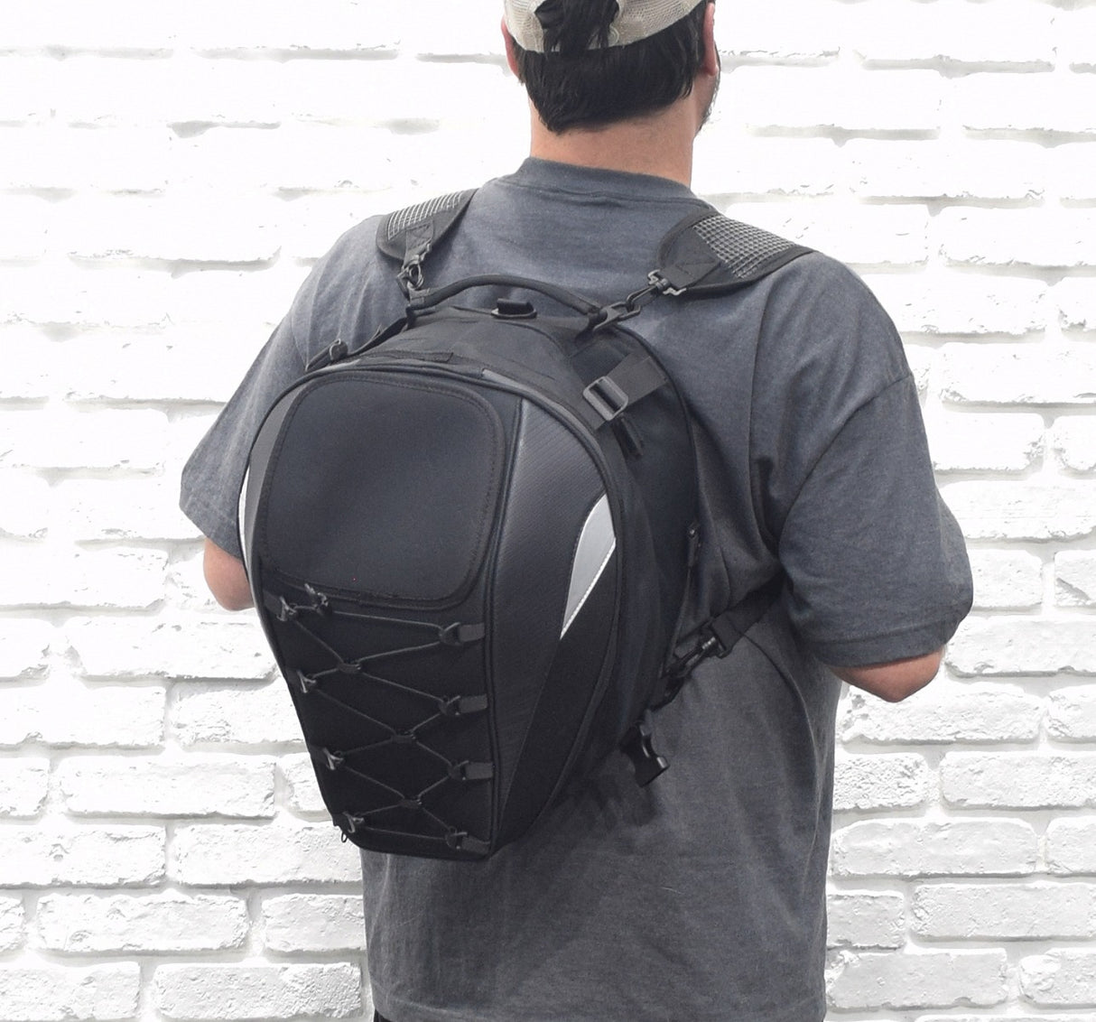 A man wearing a backpack and holding a Tail Bag for Electric Bikes, showcasing its size and design with webbing straps and pinch-buckles for secure attachment.