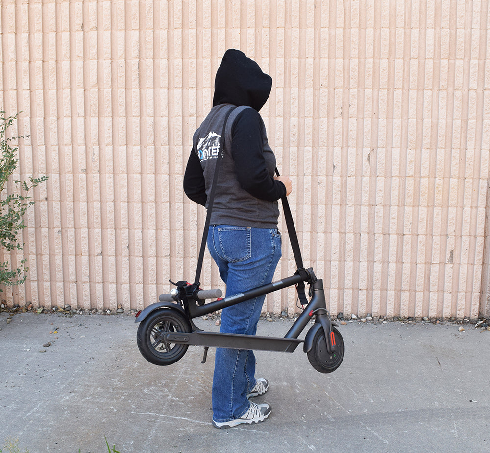 Nylon Shoulder Carrying Strap for Folding Scooters shown with a person holding a scooter. The strap's adjustable length and pinch buckles are visible, designed for easy scooter transport.