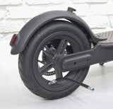 5” Black Rubber Inner Tube Valve Extender attached to a black scooter tire, showcasing the extender's black braided nylon tube and Schrader valve connectors at both ends.