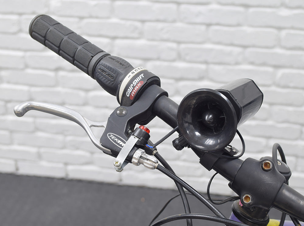 Electric Horn for Bikes & Scooters mounted on a bicycle handlebar, showcasing its compact design and easy access push button for activation.