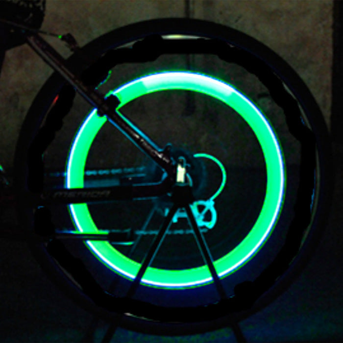 Firefly Valve Stem Light for Bikes & Scooters, featuring a bicycle wheel with vibrant green lights, illuminating brilliantly as the wheel spins, enhancing visibility during low light conditions.