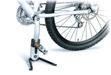 Close-up of the FlashStand Fat Portable Bike Repair Stand attached to a bicycle crank arm, illustrating its compact, lightweight design suitable for supporting mountain bikes on flat surfaces.