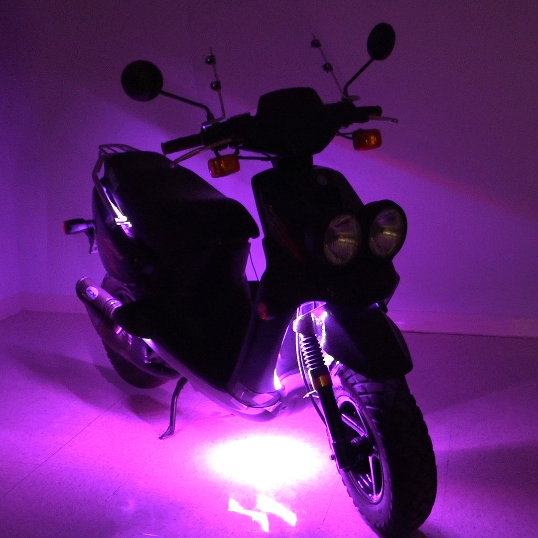 Multi-Color LED Light Kit for Street Scooters, shown on a black scooter with purple lights, highlighting the versatility and brightness of the lights, especially around the tire area.