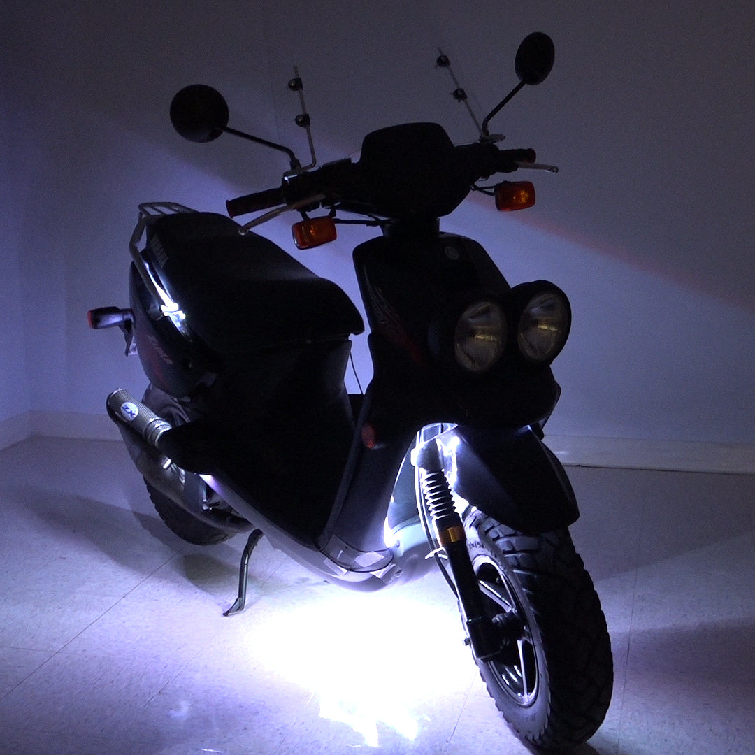 Multi-Color LED Light Kit for Street Scooters, shown on a black scooter with lights on, highlighting its illuminated headlights and glowing tires, perfect for enhancing safety and style during rides.