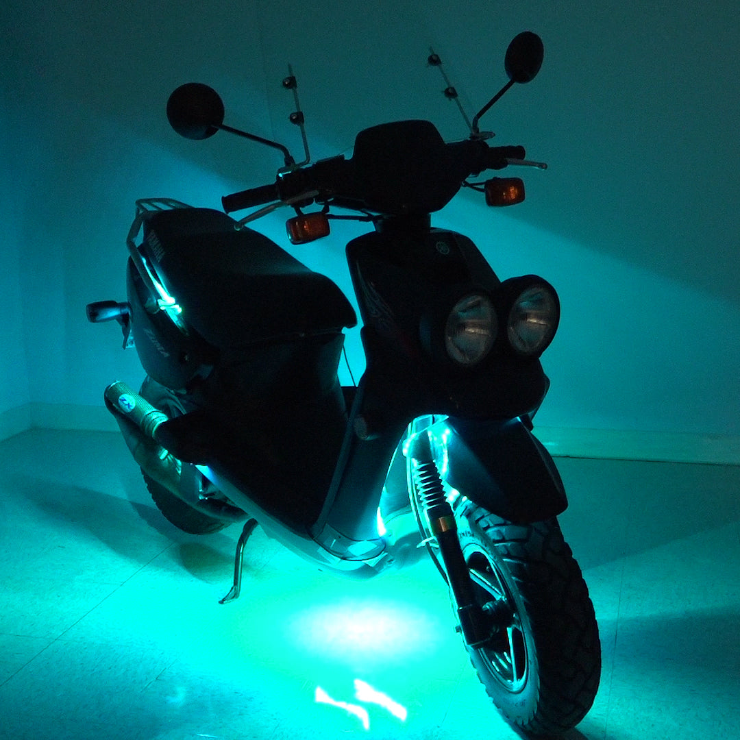 Multi-Color LED Light Kit for Street Scooters, shown installed on a scooter with lights on, illuminating the wheels and headlight for enhanced visibility and aesthetic appeal.