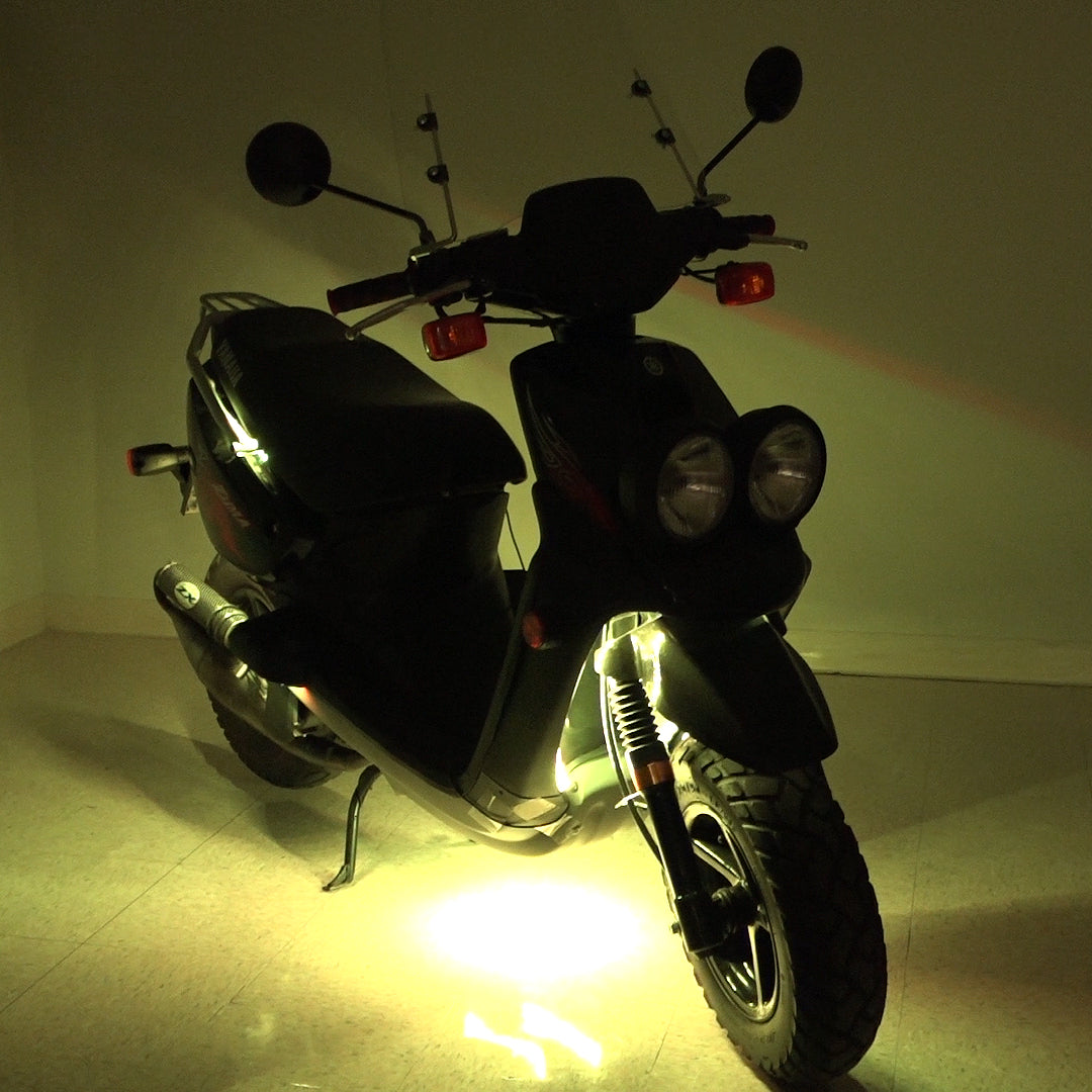 Multi-Color LED Light Kit for Street Scooters displayed on a scooter in a dark room, showcasing illuminated tires and bright LED strips, highlighting the product's vibrant and customizable lighting features.